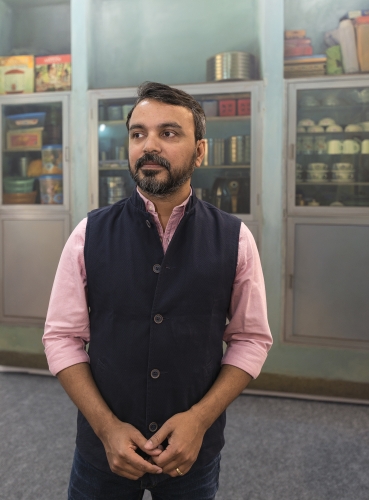 Abir Karmakar, the artist, dressed in Nehru jacket standing in front of his work at India Art Fair 2018